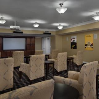 A conference room arranged with comfortable chairs and a projector screen, ready for a meeting or presentation.