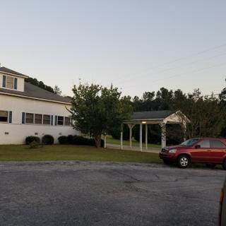 A scenic view of a house with a gazebo and parked car during the evening.
