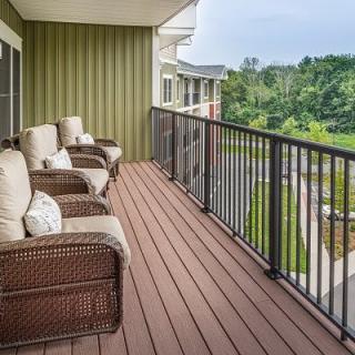 A cozy balcony with comfortable wicker chairs overlooking a green landscape.