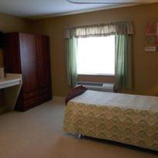 A simple bedroom with a single bed, wardrobe, and a window with curtains.
