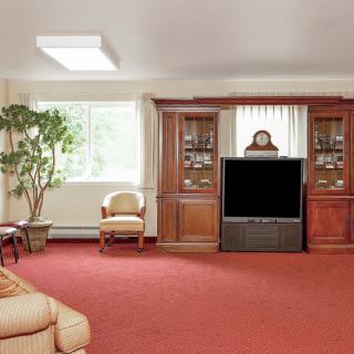 A cozy living room with a large TV, bookshelves, and comfortable seating.