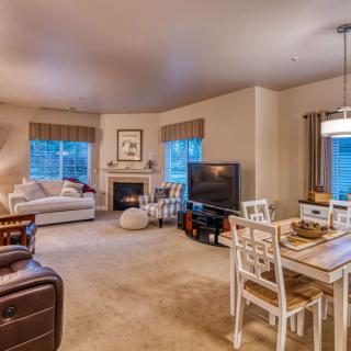 A cozy living and dining space featuring a sofa, fireplace, dining table, and a television.