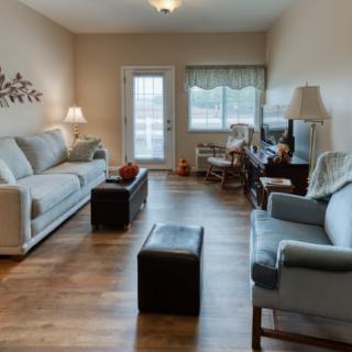 A cozy living room with sofas, lamps, and hardwood flooring.
