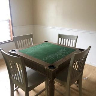 A dining area featuring a square green felt game table with four chairs.