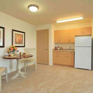A cozy kitchen and dining area with a table, chairs, fridge, and cabinets.