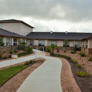 A modern building with a landscaped path under a cloudy sky.