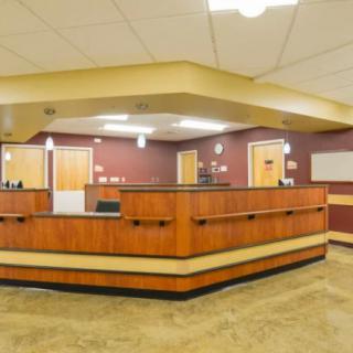 A spacious office reception area with a wooden desk and overhead lighting.