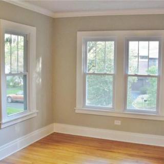A bright and airy room with large windows, showcasing a neutral color palette and hardwood flooring.