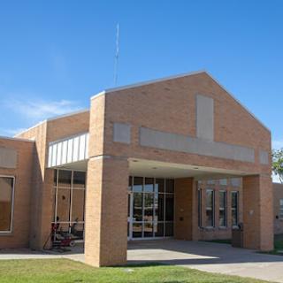 A modern brick building with large windows under a clear blue sky.