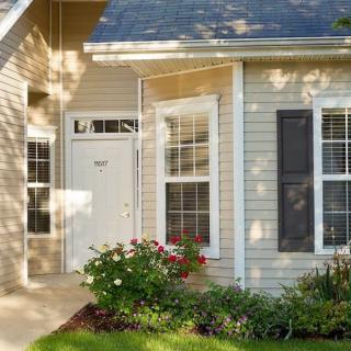 A cozy house exterior with a white front door, surrounded by windows and well-maintained landscaping.
