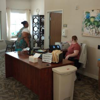 A cozy office space featuring a reception desk with two individuals engaged in conversation.