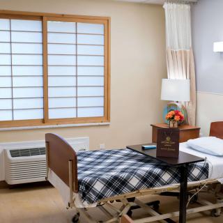 A clean and well-lit hospital room with a single bed and bedside table.