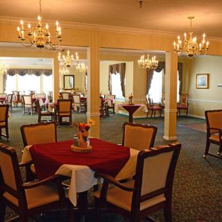 An elegant dining area with chandeliers and well-arranged tables in a warm, inviting atmosphere.
