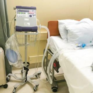A hospital room featuring a bed and medical ventilator equipment.
