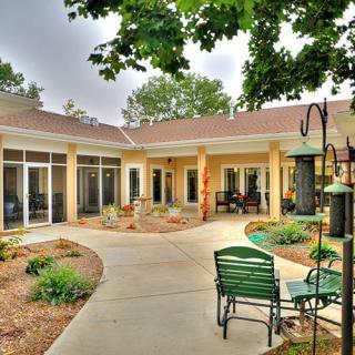 A charming patio area with outdoor seating surrounded by a garden and trees.