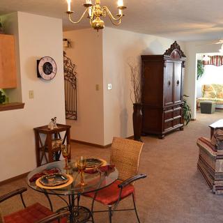 A cozy dining and living room area with a chandelier, table setting, and wooden furniture.