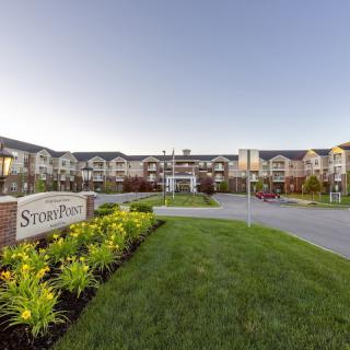A well-landscaped residential apartment complex with visible signage at the entrance.