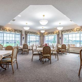 A spacious dining room with multiple tables and chairs, featuring large windows and elegant lighting.
