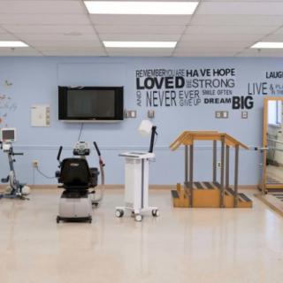 A well-equipped physical therapy room featuring various rehabilitation devices and motivational quotes on the wall.