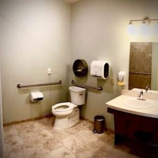 A clean and well-organized public restroom featuring a toilet, sink, and mirror.