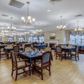 An elegant dining area with neatly arranged tables and chairs under ornate chandeliers.