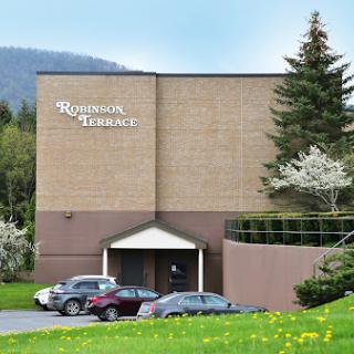 A modern business building surrounded by greenery and parked cars.