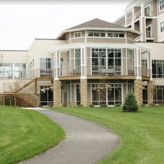 A modern building with large windows and a pathway leading up to it, surrounded by a well-maintained lawn.