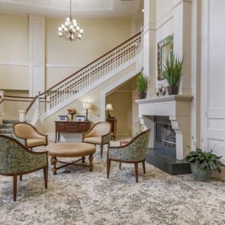 A luxurious lobby with elegant furniture, a grand staircase, and a cozy fireplace.