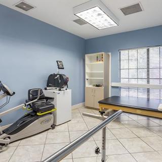A well-equipped therapy room with exercise machines and a treatment table.