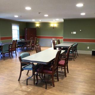 An empty community dining area with multiple tables and chairs arranged neatly.