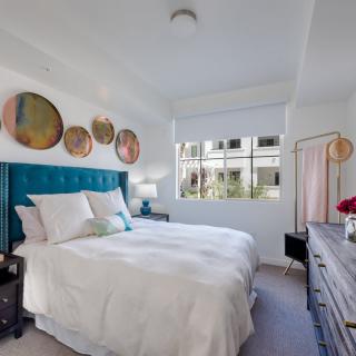 A modern bedroom with stylish decor, featuring a teal headboard and circular wall art.