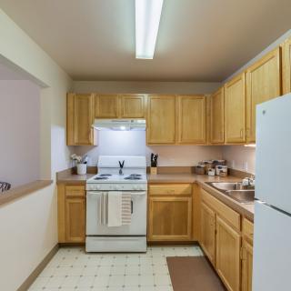 A cozy kitchen with wooden cabinets, a stove, refrigerator, and ample countertop space.