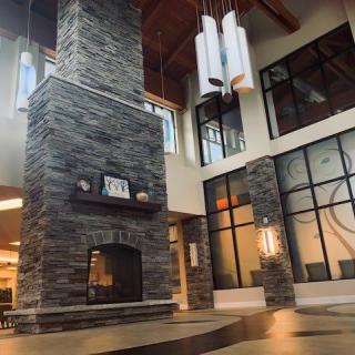A modern lobby featuring a large stone fireplace and contemporary chandeliers.