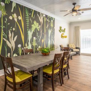 A stylish dining room with a botanical wallpaper and wooden furniture.