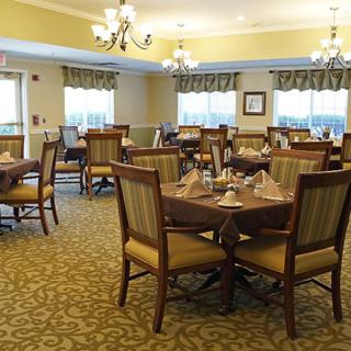 An elegant dining room setup with neatly arranged tables and chairs under chandeliers.