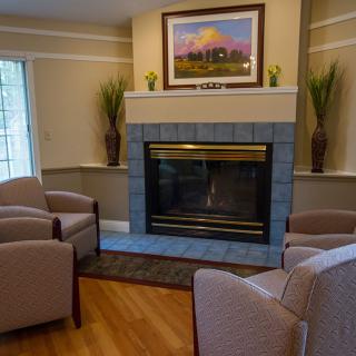 A cozy living room with a fireplace surrounded by comfortable chairs and tasteful decor.