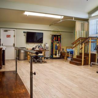 A spacious physical therapy room equipped with various rehabilitation tools and exercise equipment.