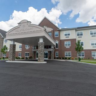 A three-story hotel with a covered entrance and brick facade under a partly cloudy sky.