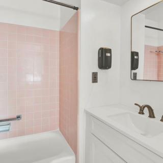 A modern bathroom featuring pink tiles with a bathtub and sleek fixtures.