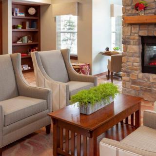A cozy living room with armchairs, a stone fireplace, and a wooden coffee table adorned with a plant.