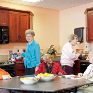 A group of seniors socializing in a shared kitchen space.