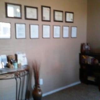 A neatly decorated office corner with framed wall art and a small console table.