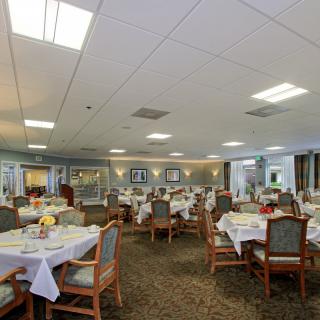 A spacious dining area with neatly arranged tables and chairs under bright lighting.