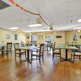 An indoor dining area with empty tables and chairs, adorned with festive decorations.