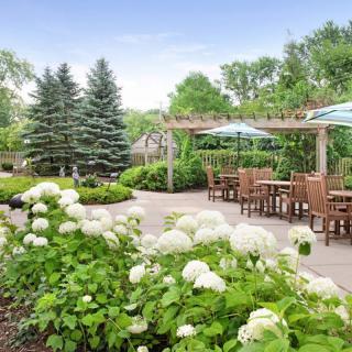 A beautifully landscaped garden patio with outdoor seating, blooming hydrangeas, and a pergola.