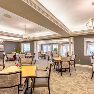 A spacious and elegantly designed dining room with multiple tables and chairs arranged neatly.