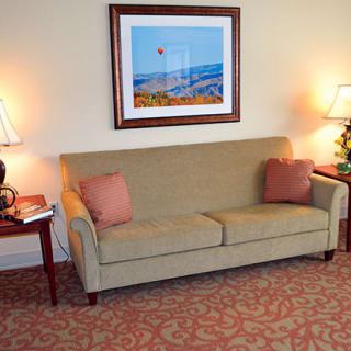A cozy living room setup with a sofa, lamps, and artwork on the wall.