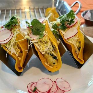 Three delicious tacos filled with fresh ingredients and topped with radishes and cilantro.