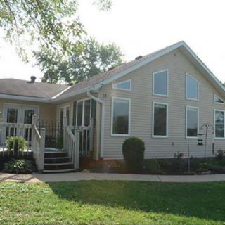 A suburban single-story house with a well-maintained yard and large windows.