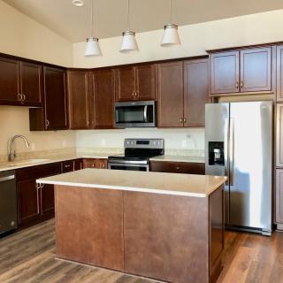 A modern kitchen with brown cabinets, stainless steel appliances, and a central island.